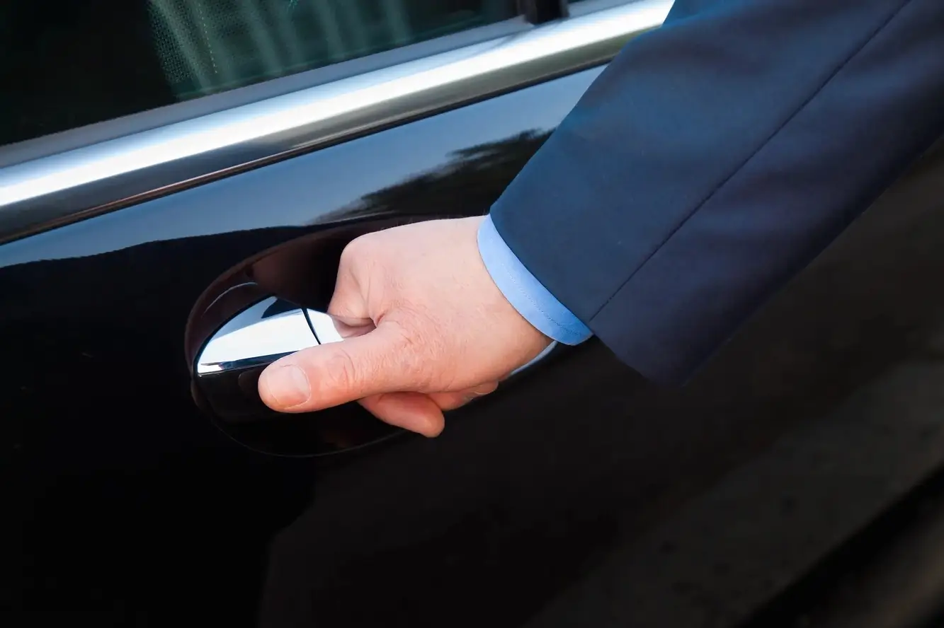 Professional driver opening a vehicle door, exemplifying Colorado car services for a private client.